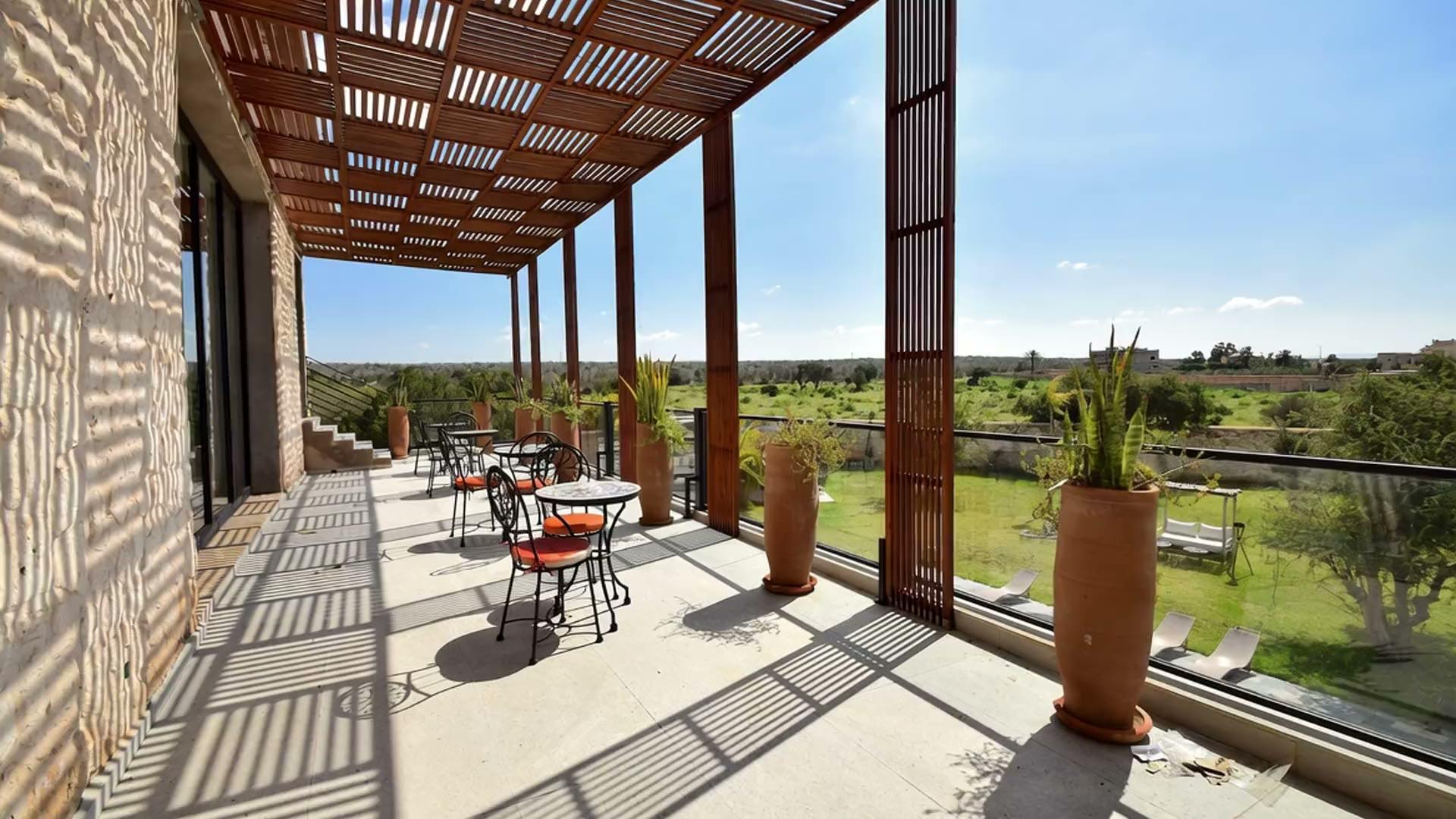Premier plan de la visite : la terrasse sous la pergola à lames.