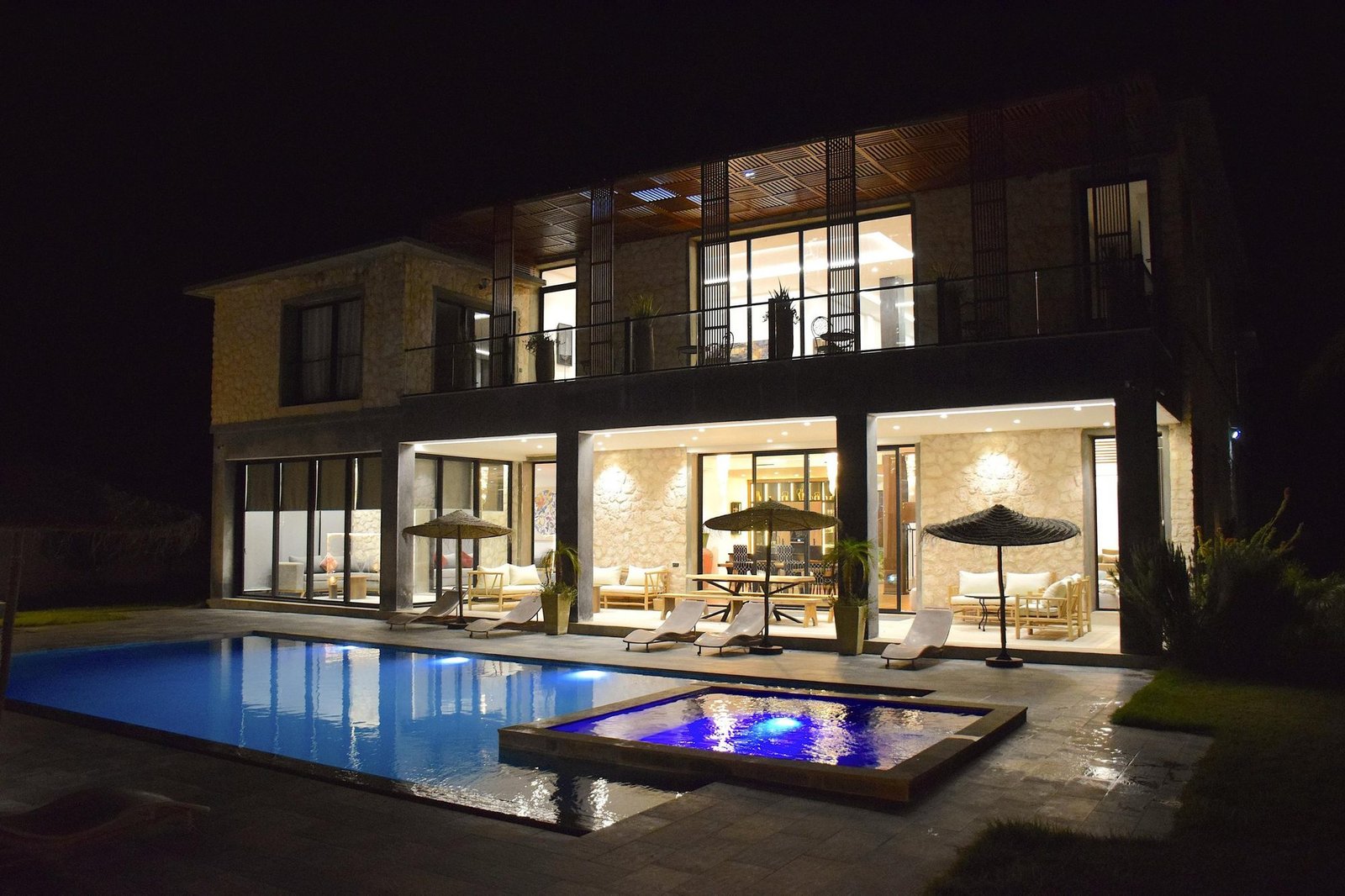 La villa Octagon illuminée à la nuit tombée, avec le jacuzzi au premier plan