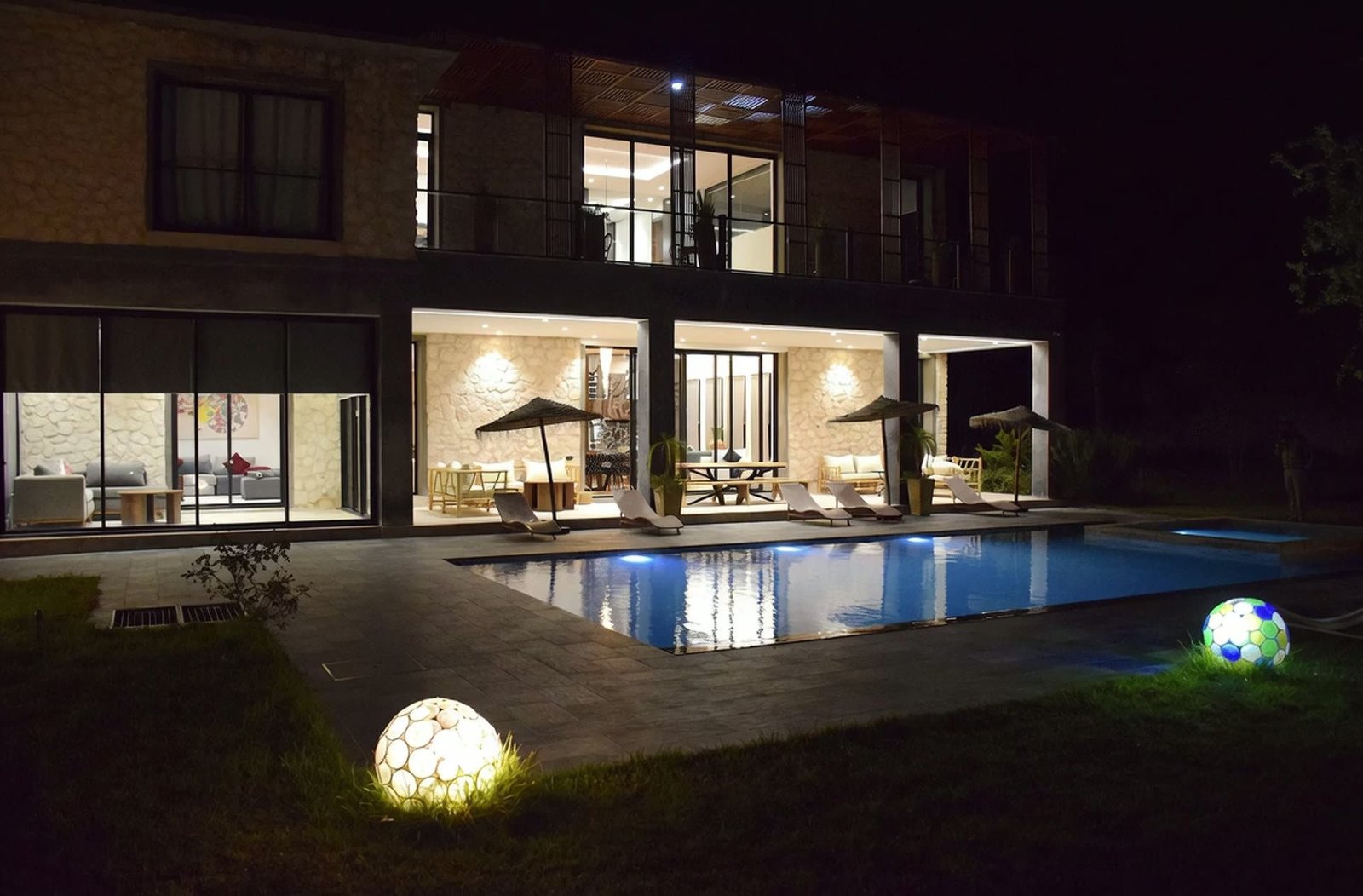 Vue plongeante sur la piscine éclairée de la villa Octagon à la nuit tombée